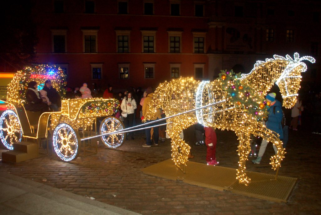 Dorożka konna świecąca niezliczonymi lampkami na placu Zamkowym w Warszawie
