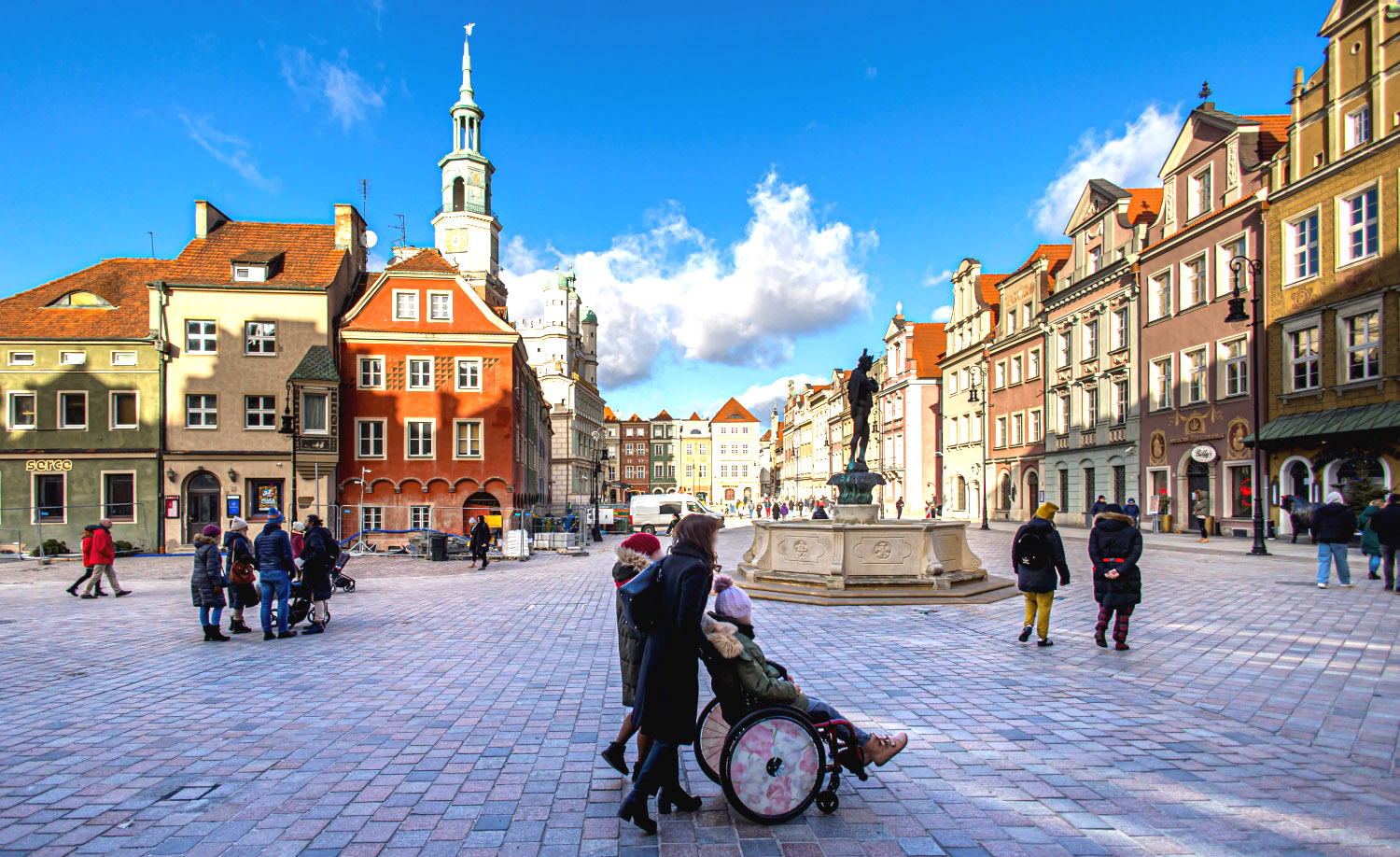 Stary Rynek w Poznaniu. Na pierwszym planie przechodnie w wózku inwalidzkim